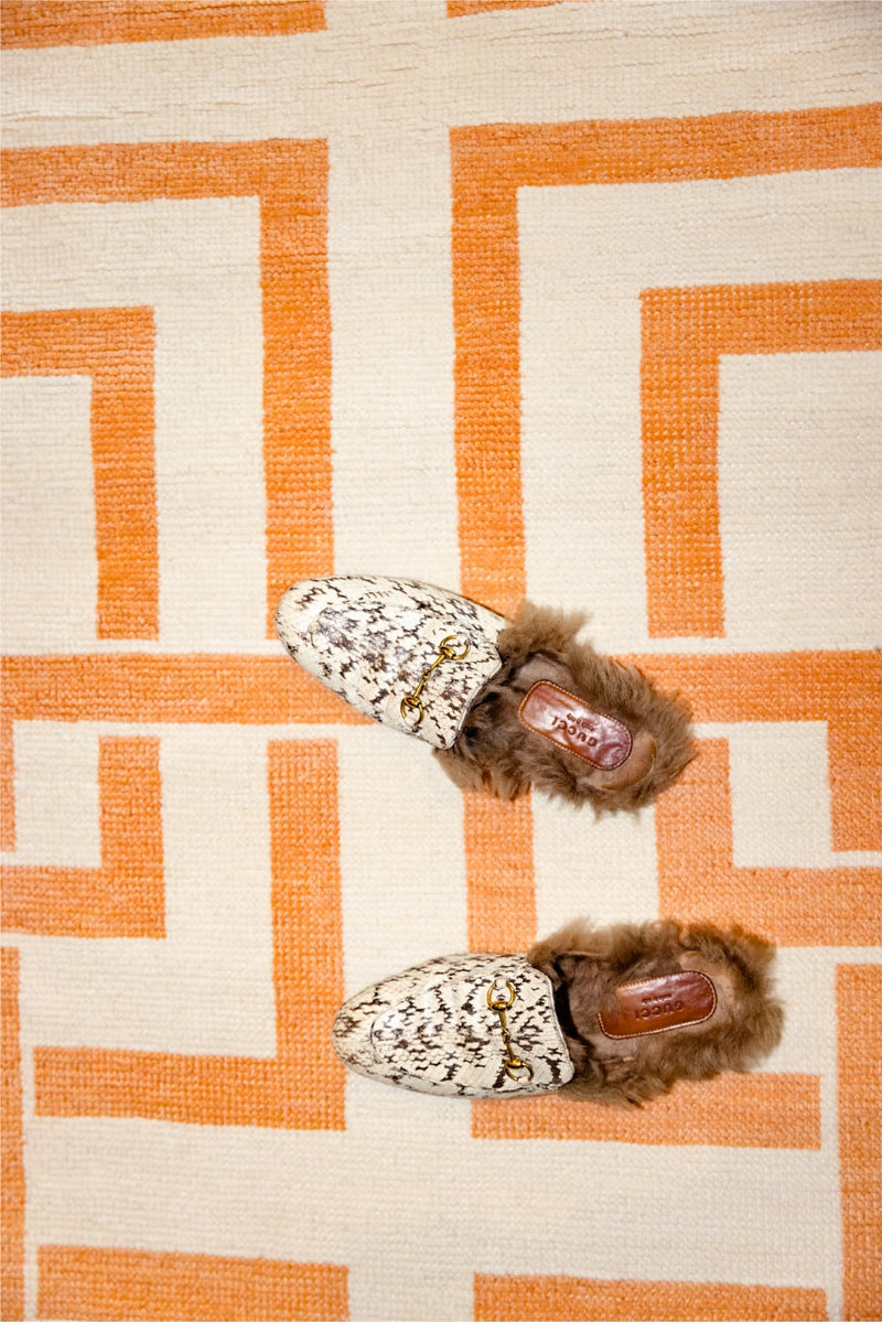 Pair of slippers with fur trim on a geometric patterned rug