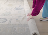Person unrolling a rug in purple sweater