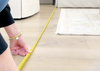 person measuring floor area for rug sizing